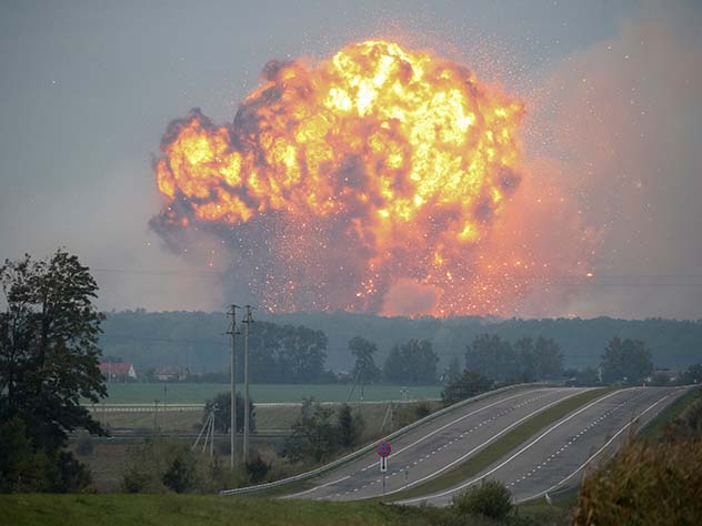 Smoke and flames rise over a warehouse storing ammunition for multiple rocket launcher systems at a military base in the town of Kalynivka
